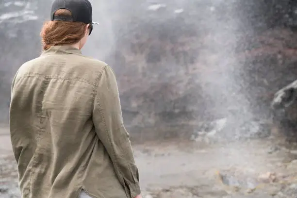 Woman standing back from danger as ocean starts to spout through blowhole