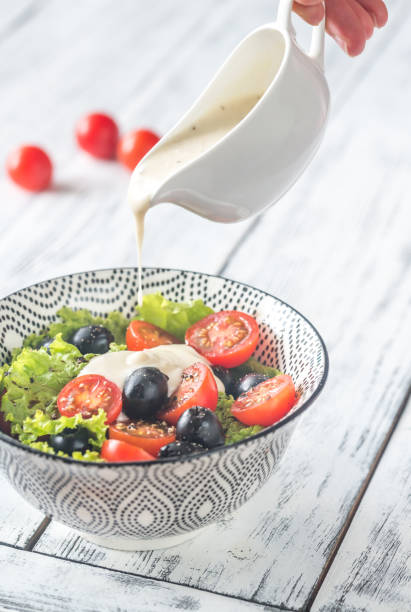 istock A hand pouring salad dressing onto Caesar salad 813246900