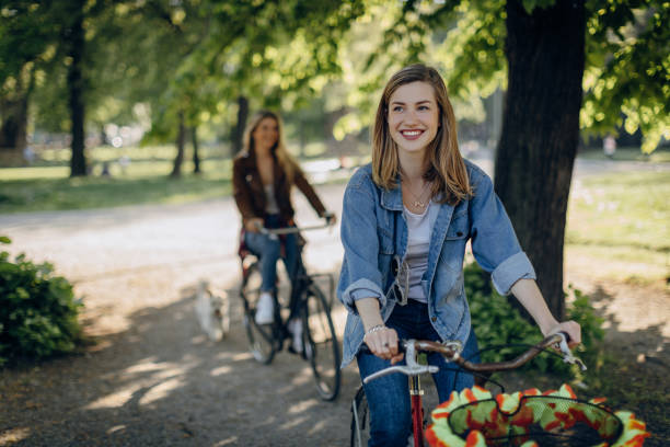 istock Two best friends riding bicycles in a park 813249108