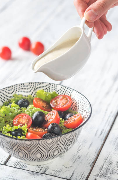 istock A hand pouring dressing onto Caesar salad 813251210