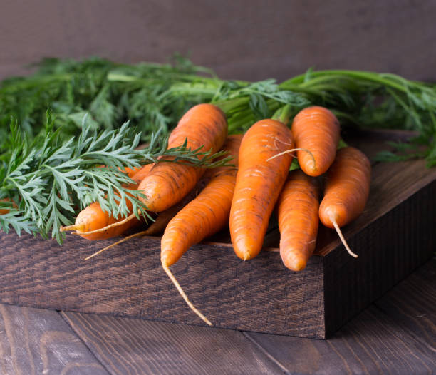 свежая морковь пучок на деревенском деревянном фоне - carotene healthy eating macro close up стоковые фото и изображения