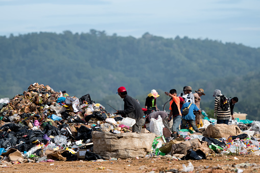 Kota Kinabalu, Malaysia - 09 July, 2017: People looking through rubbish on landfill site in Sabah, Borneo. They scavenge here daily for useful items that can be resold and recycle. In Malaysia, the absence  of an integrated waste management system resulted with more than 10.40  million tonnes of municipal solid waste being disposed off into landfills annually.