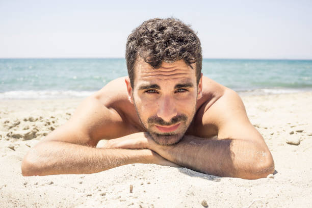 istock Serious man laying on the sand 813309318