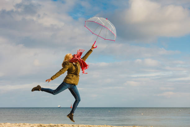 istock Woman jumping with transparent umbrella on beach 813311428