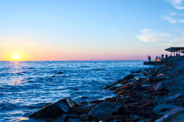 Silhouette of the fisherman over the sunrise and stones.