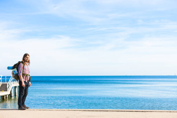 istock Man hiker with backpack tramping by seaside 813329774