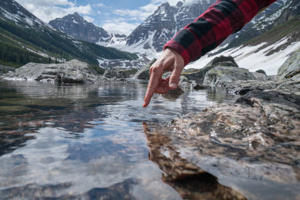 istock Finger touches surface of mountain lake 813343630