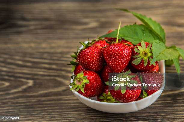 Small White China Bowl Filled With Succulent Juicy Fresh Ripe Red Strawberries On An Old Wooden Textured Table Top Fresh Strawberries Strawberries On A Wooden Table Stock Photo - Download Image Now