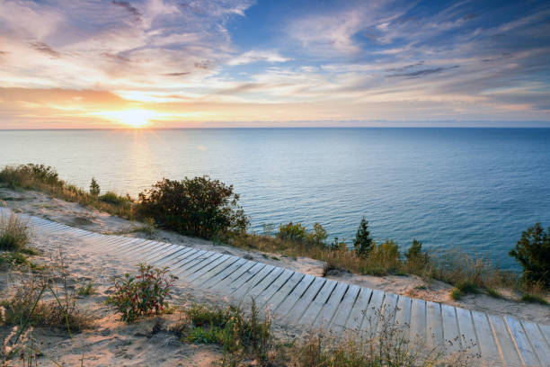 Sunset Over Lake Michigan and Sleeping Bear Dunes A colorful sunset over Lake Michigan shines its light on this boardwalk on Empire Bluff Trail near Empire Michigan. This trail overlooks Sleeping Bear Dunes lake michigan stock pictures, royalty-free photos & images