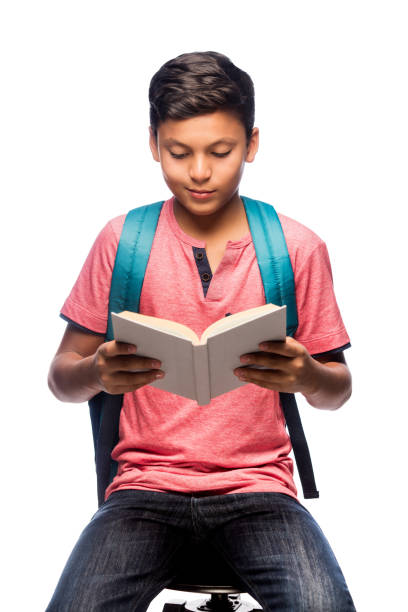 Latin schoolboy sitting and reading a book stock photo