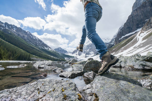 istock Hiker jumps rock to rock on mountain lake 813385674