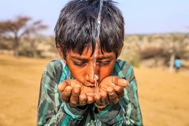 istock Indian young boy drinking fresh water, desert village, Rajasthan, India 813386590
