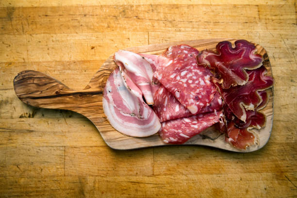 Small Charcuterie Plate with Ham, Salami and Prosciutto Delicious cold cuts of cured meat, ham or bacon, salami and prosciutto on a rustic cutting board. charcuterie stock pictures, royalty-free photos & images
