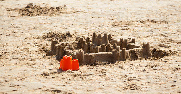 grand château de sable et un seau sur la plage à brancaster norfolk en angleterre - sandcastle beach norfolk sand photos et images de collection