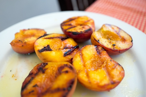 A dessert of grilled peaches is visible on a white plate with grill marks, July 4, 2017