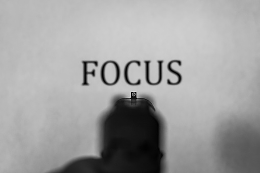 Handgun pointed at the word: FOCUS