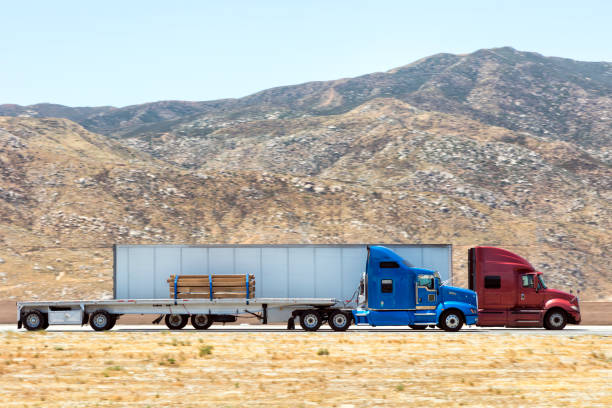 Fast and powerful heavy-lift modern semi trucks with a full size trailer at the turn of mountain scenic highway, blurred motion, western USA, California.\n\n