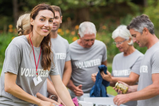 une bénévole heureux en regardant boîte de donation - bénévole photos et images de collection