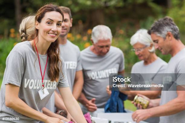 Happy Volunteer Looking At Donation Box Stock Photo - Download Image Now - Volunteer, Charity and Relief Work, Community Outreach