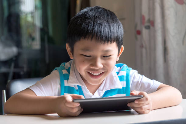 istock Young asian boy happy, he browses the internet on a tablet computer at home. 813530762