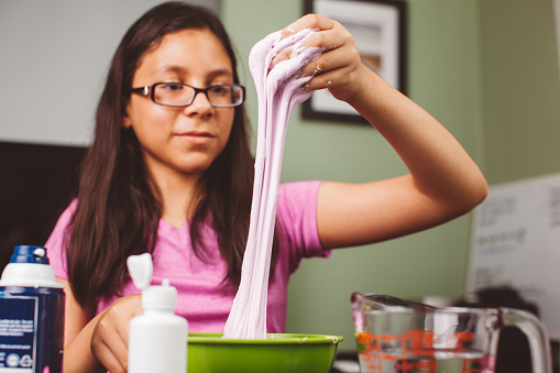 Young child doing an experiment and creating fluffy slime.