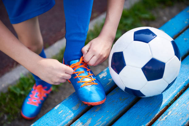 Boy football soccer tying laces of boots on bench Boy football soccer tying the laces on the boots on bench football boot stock pictures, royalty-free photos & images