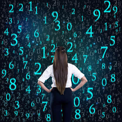 Rear view of businesswoman with hands on hip in front of binary code background
