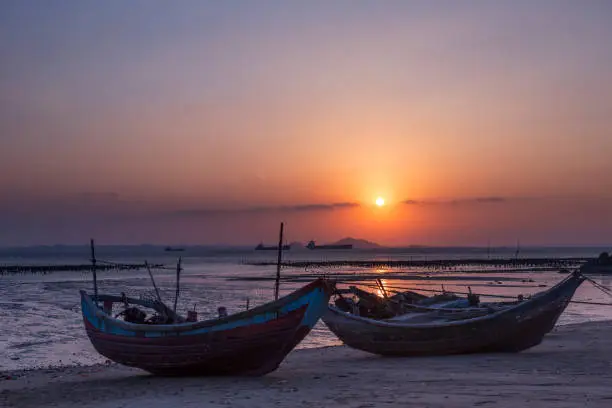scenic view of sandy beach with two fishing boats on during sunset,Fujian province,China.