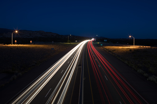 Streaky headlights and tail lights of cars going into the distance at night with street lights in New Mexico