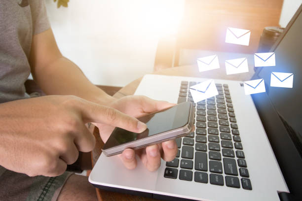 istock Man used cellphone to sent email data on laptop on wooden table 813612946
