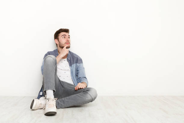 istock Pensive man sitting on floor and looking upwards 813619222