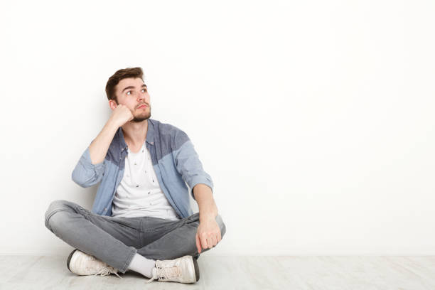 istock Pensive man sitting on floor and looking upwards 813619258