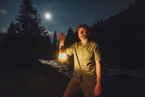 istock Man with gas lantern standing near the river at night 813621608