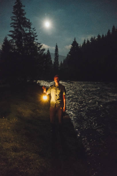 istock Man with gas lantern standing near the river at night 813621642
