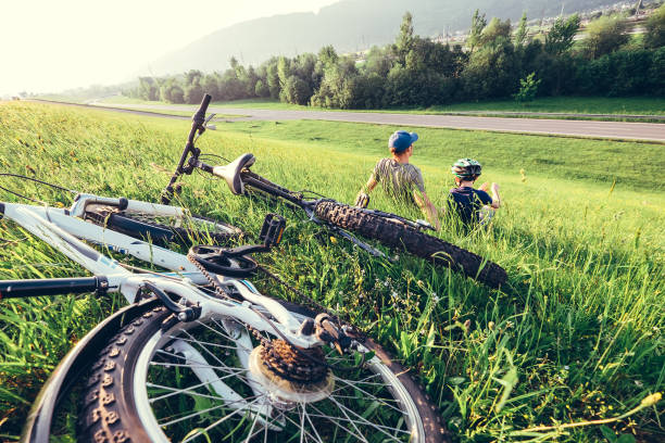 istock Father and son rest together in high green grass after bicycle walk 813628552