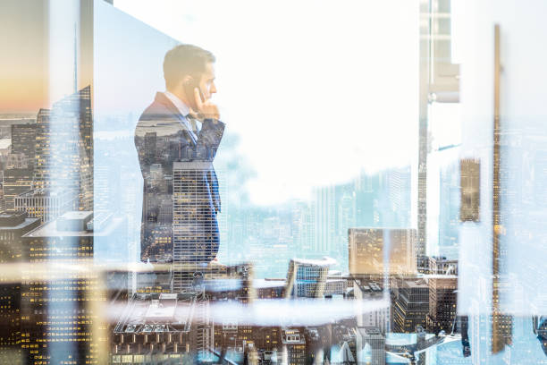 istock Businessman talking on a mobile phone while looking through window in NY 813629086