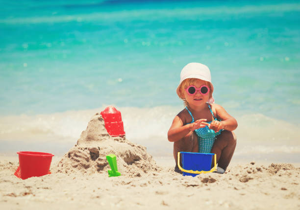 istock cute little girl play with sand on beach 813641780