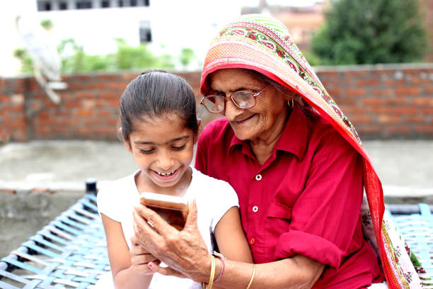 petit-enfant et sa grand-mère à l’aide de smartphone - global village photos et images de collection