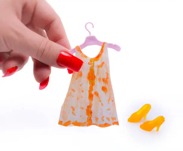 Woman holding miniature dress on plastic coat hanger painted by contributor with matching plastic fashion doll heels