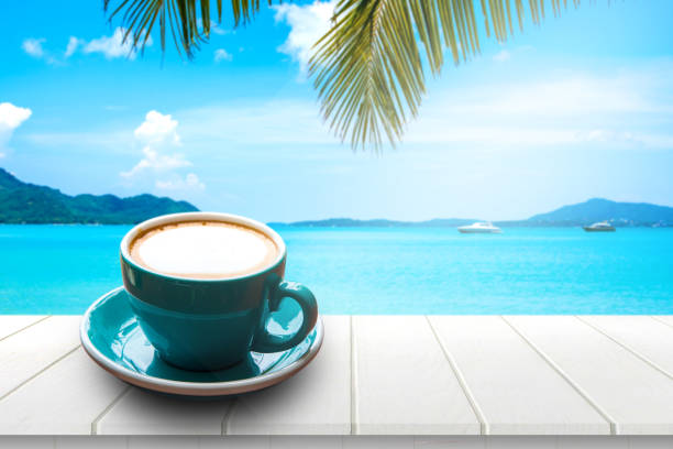 istock Coffee in cup on wooden table with sea view background in summer. 813645928