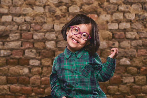 Cute Portrait of a Beautiful Down Syndrome young girl with glasses, dark hair and a green check shirt with an old Brown Brick Wall Stellenbosch Cape Town South Africa