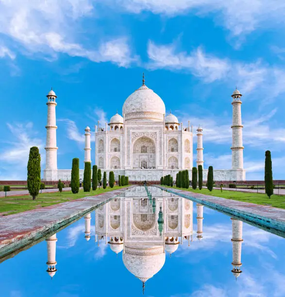 Amazing view on the Taj Mahal in sun light with reflection in water. The Taj Mahal is an ivory-white marble mausoleum on the south bank of the Yamuna river. Agra, Uttar Pradesh, India.