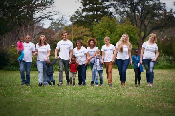 Volunteering is a work of heart Shot of a group of volunteers working with children walking for a cause stock pictures, royalty-free photos & images