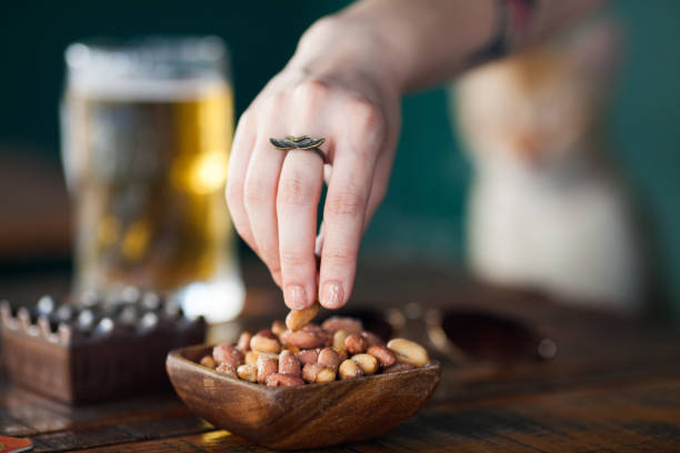 la mano della donna sta prendendo arachidi salate - beer nuts foto e immagini stock