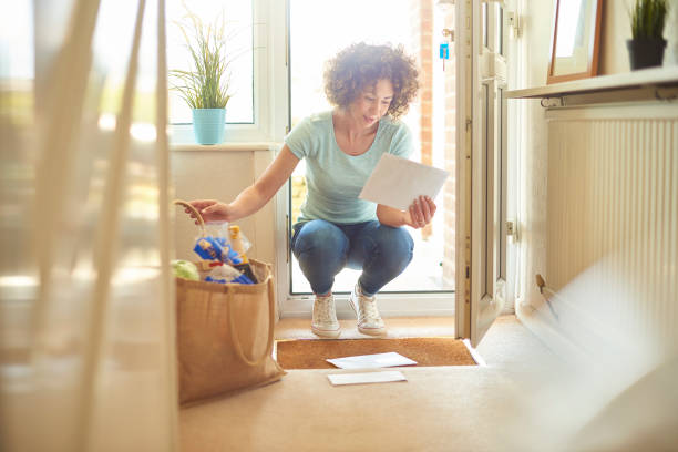 coming home to letters on the mat a woman returns home from the shops and finds some letters on the mat . She bends down to open them . key doormat stock pictures, royalty-free photos & images