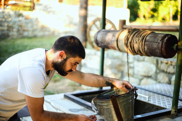istock Young man drinking water from draw well 813704042