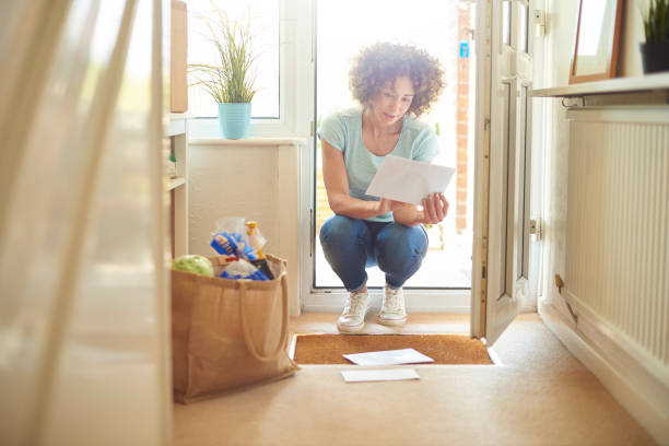 home from shopping a woman returns home from the shops and finds some letters on the mat . She bends down to open them and have a good read key doormat stock pictures, royalty-free photos & images