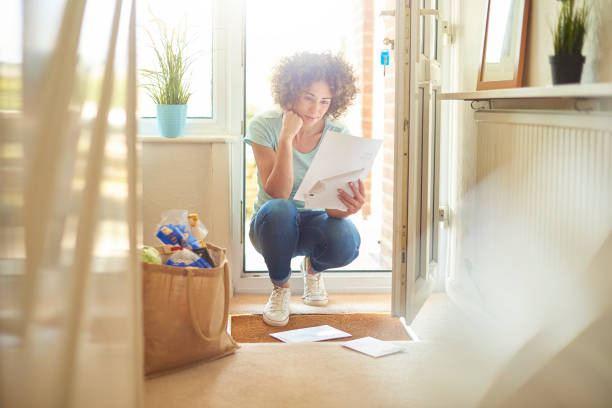 letters on the mat a woman returns home from the shops and finds some letters on the mat . She bends down to open them and have a good read key doormat stock pictures, royalty-free photos & images