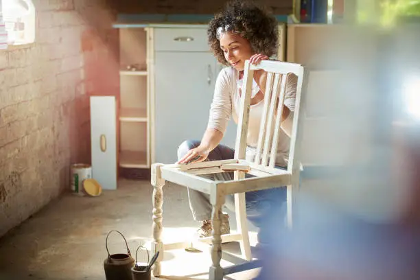 a woman restores and improves an old wooden chair in her workshop