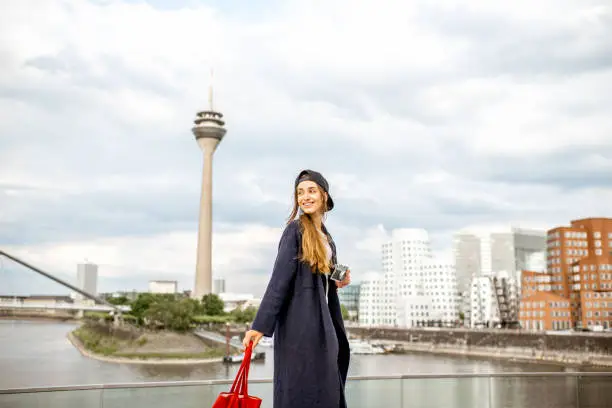 Young woman tourist standing with photo camera with famous television tower and modern buildings in Dusseldorf city, Germany